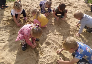 dzieci badają właściwości piasku na terenie ogródka "Słoneczna Akademia"